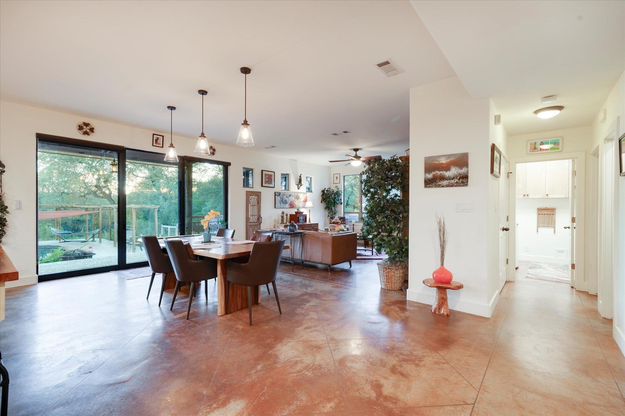 Dining and living area at 8300 Lime Creek Road with a hallway leading toward the entry, warm stained-concrete floors, and sliding doors opening onto the rear patio
